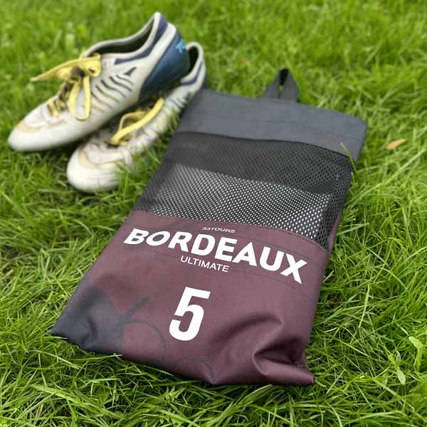 sac à crampons posé sur l'herbe avec une paire de crampons en arrière plan