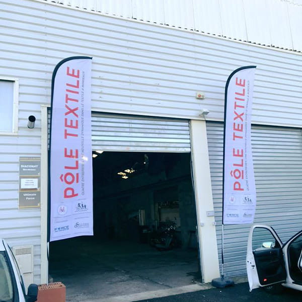 industrieel gebouw en twee veer banners met 'pole textile' geschreven