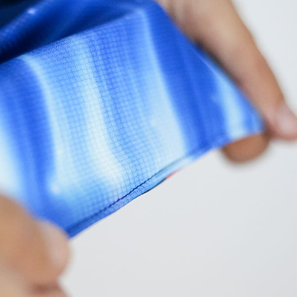 mains étirant un tissu sublimé bleu