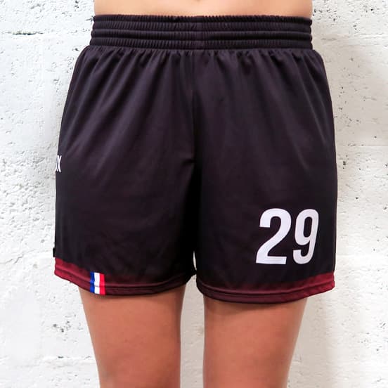 front view of woman lower body wearing feminine black shorts in front of a white wall